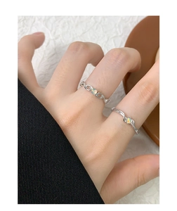 Dettaglio di due anelli in argento S925 con opali, design a catena e a onde sottili