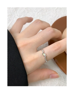 Gros plan sur une bague en argent S925 avec opale et lignes croisées torsadées sur le doigt