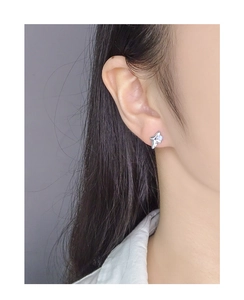 Close-up of S925 sterling silver star stud earring with blue opal stone on model's ear