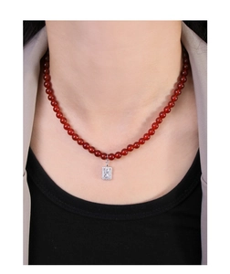 Detail of red agate beaded necklace with a sparkling rectangular pendant on a model