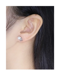 Macro view of sterling silver bow earrings with round white pearl on a model's ear