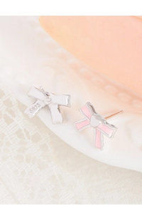 Detail shot of S925 silver bow earrings with pink enamel on a vintage white plate