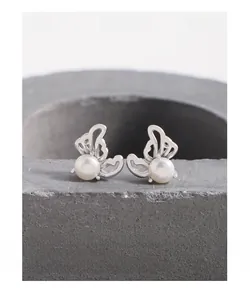 Macro shot of S925 silver hollow wing stud earrings with white freshwater pearls