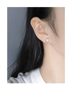 Detailed view of the S925 silver bow and pearl stud earring on model's ear