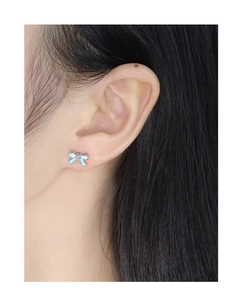 Detail of light blue bow stud earring worn on ear with polished silver base