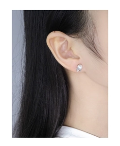 Close-up of elegant S925 silver bow stud earrings with lustrous white pearls on ear