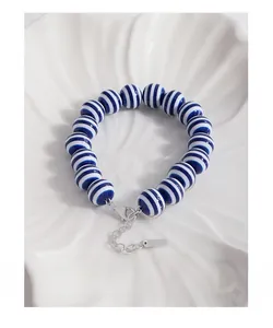 Macro detail of S925 sterling silver lobster clasp and blue striped beaded bracelet
