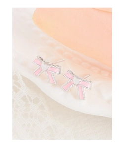 Macro shot of silver bow earrings with pink enamel inlay and heart detail on lace