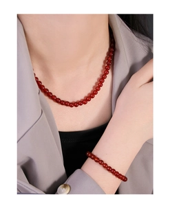 Elegant red agate beaded necklace and bracelet set worn with a stylish grey suit