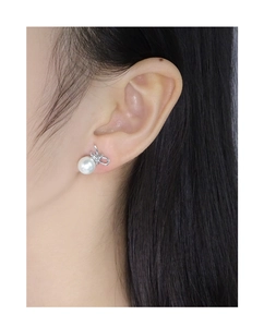 Close-up of S925 silver bow stud earring with a round white pearl on female model