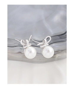 Close-up of S925 silver bow earrings with round white pearls on a textured background