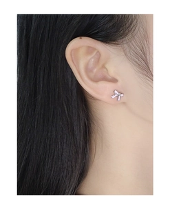 Detail of S925 silver bow stud earrings with pink enamel glaze on a female model