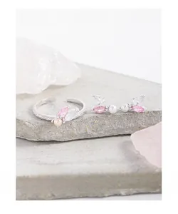 Detail of silver S925 jewelry set with pink zircons and pearls on stone surface