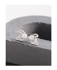 Macro detail of hollow wing silver earrings with centered white pearl on stone