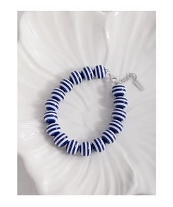 Macro detail of S925 sterling silver tag and blue striped beads on the bracelet