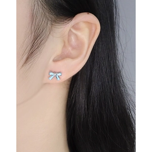 S925 silver bow stud earrings with light blue enamel finish shown on model