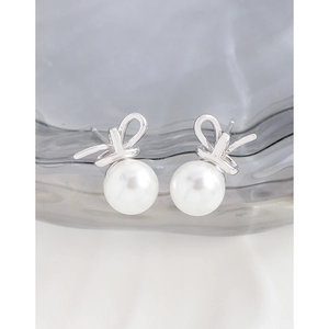 Elegant S925 silver bow stud earrings with white pearls on a textured glass surface