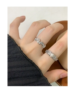 Detail of silver rings featuring textured lava surface and marquise zircon stones