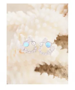 Detail of star and heart stud earrings with moonstone on a decorative white coral