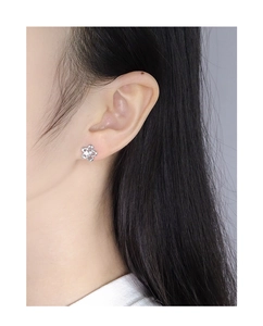Close-up of minimalist silver flower earring with zircon details worn on earlobe