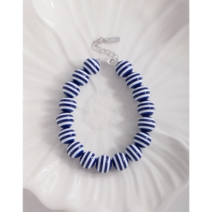 Navy blue striped bead bracelet with S925 sterling silver clasp on a white plate