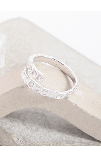 Macro shot of silver scale texture open ring with small zircon on stone background