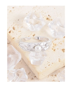 Close-up of S925 silver ring with hammered texture and round pearl on a stone surface