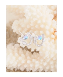 Macro shot of S925 silver star earrings with moonstone and pearls on white coral background