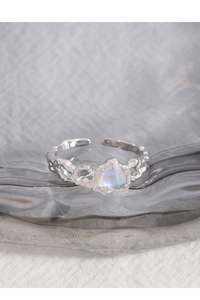 Dettaglio macro dell'anello in argento con pietra di luna a cuore e trama liquida