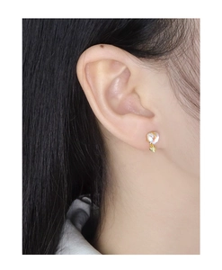 Detail of moonstone stud earrings with gold heart charm shown on a female model