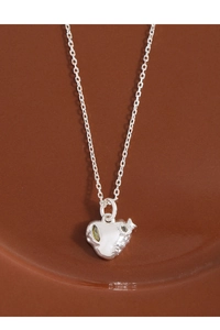 Detailed view of silver heart pendant with organic texture and olive green zircon stone