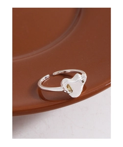 Close-up of S925 silver heart ring with sparkling champagne zircon on ceramic plate