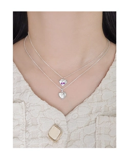 Detail of layered S925 silver necklaces with heart pendants and bow zircon accents