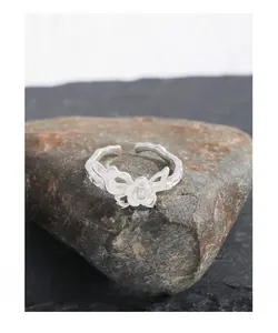 Detail shot of a S925 silver ring with rose and butterfly motifs on a natural stone