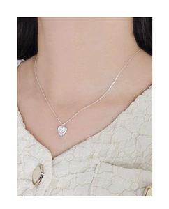 Close-up of pink zircon heart pendant with bow detail on silver necklace worn by model