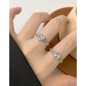 Anelli in argento con pietre di luna a cuore e tonde sulla mano di una modella