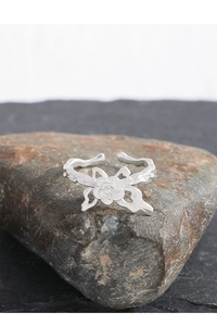 Macro shot of silver rose ring featuring realistic floral texture on a dark stone