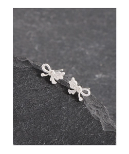 Close-up of elegant S925 sterling silver asymmetrical bow stud earrings on a dark stone