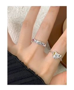 Detail of silver rings featuring zircon heart and lava texture worn on fingers
