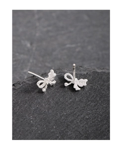 Macro view of S925 sterling silver bow earrings with hallmark on dark rock surface