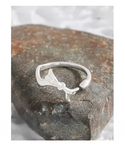 S925 sterling silver bow ring displayed on natural brown rock to show metallic texture