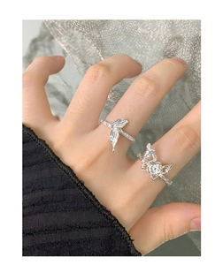 Detailed view of silver fish tail and rose butterfly textured rings worn on fingers
