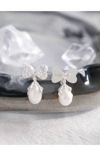 Detailed macro view of S925 silver bow earrings with teardrop pearls and hammered textures