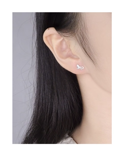 Close-up of minimalist silver bow stud earrings worn by a model for a daily look