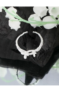 Detailed shot of textured S925 silver butterfly ring on charcoal with lily of the valley