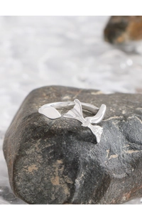 Macro detail of irregular S925 sterling silver bow ring on a natural dark grey stone