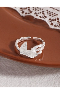 Macro shot of silver butterfly ring with texture on ceramic plate and lace detail