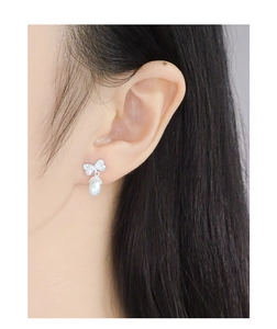 Close-up of S925 silver bow earrings with sparkling zircon and drop pearl on a model