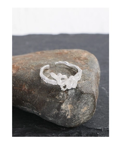Macro detail of S925 sterling silver rose flower ring with unique branch texture on rock