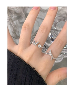 Detail of silver S925 bow and butterfly open rings worn on model fingers